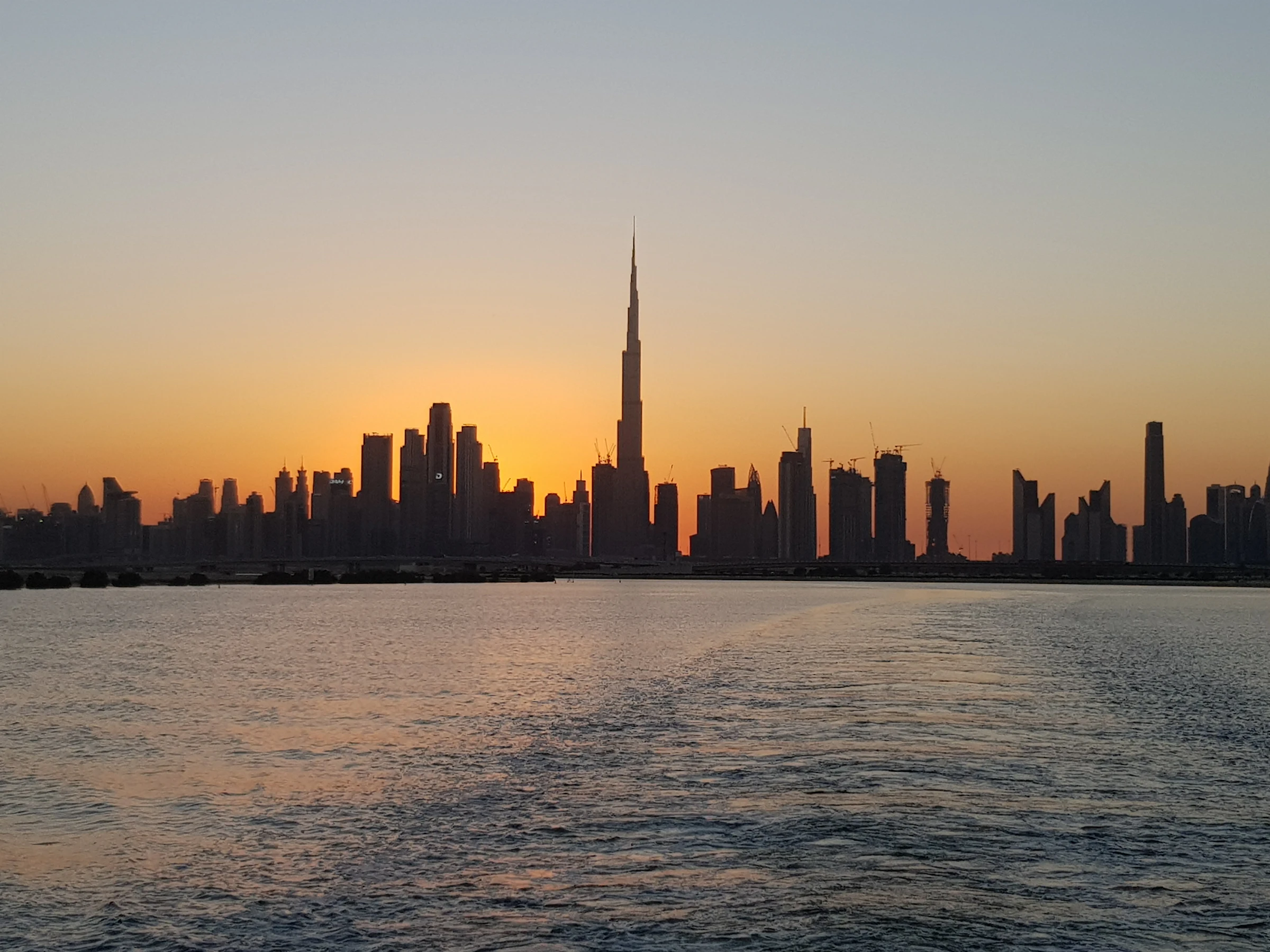 A city skyline silhouetted against a dusk sky over the water